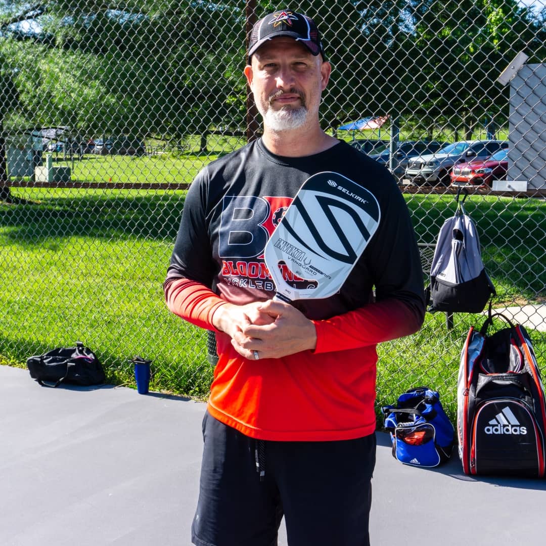 Coach Dave Martin holding a Selkirk pickleball paddle at RCA Park in Bloomington, Indiana, representing the Bloomington Pickleball Club.