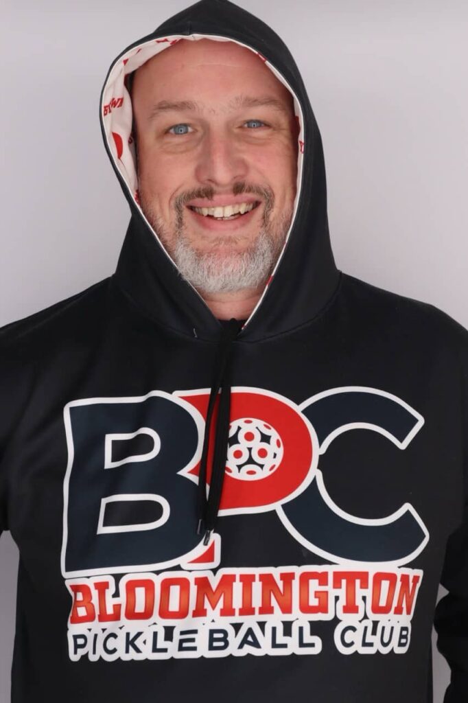 Portrait of Dave Martin, pickleball coach, wearing a Bloomington Pickleball Club hoodie