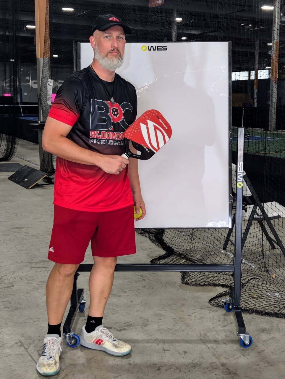 Dave Martin in a Bloomington Pickleball Club shirt holding a Selkirk LUXX paddle beside a WES swing-analysis screen