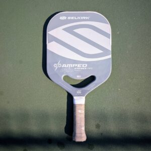 Selkirk Amped Pro Air Epic pickleball paddle with aero handle, gray and white, on a pickleball court