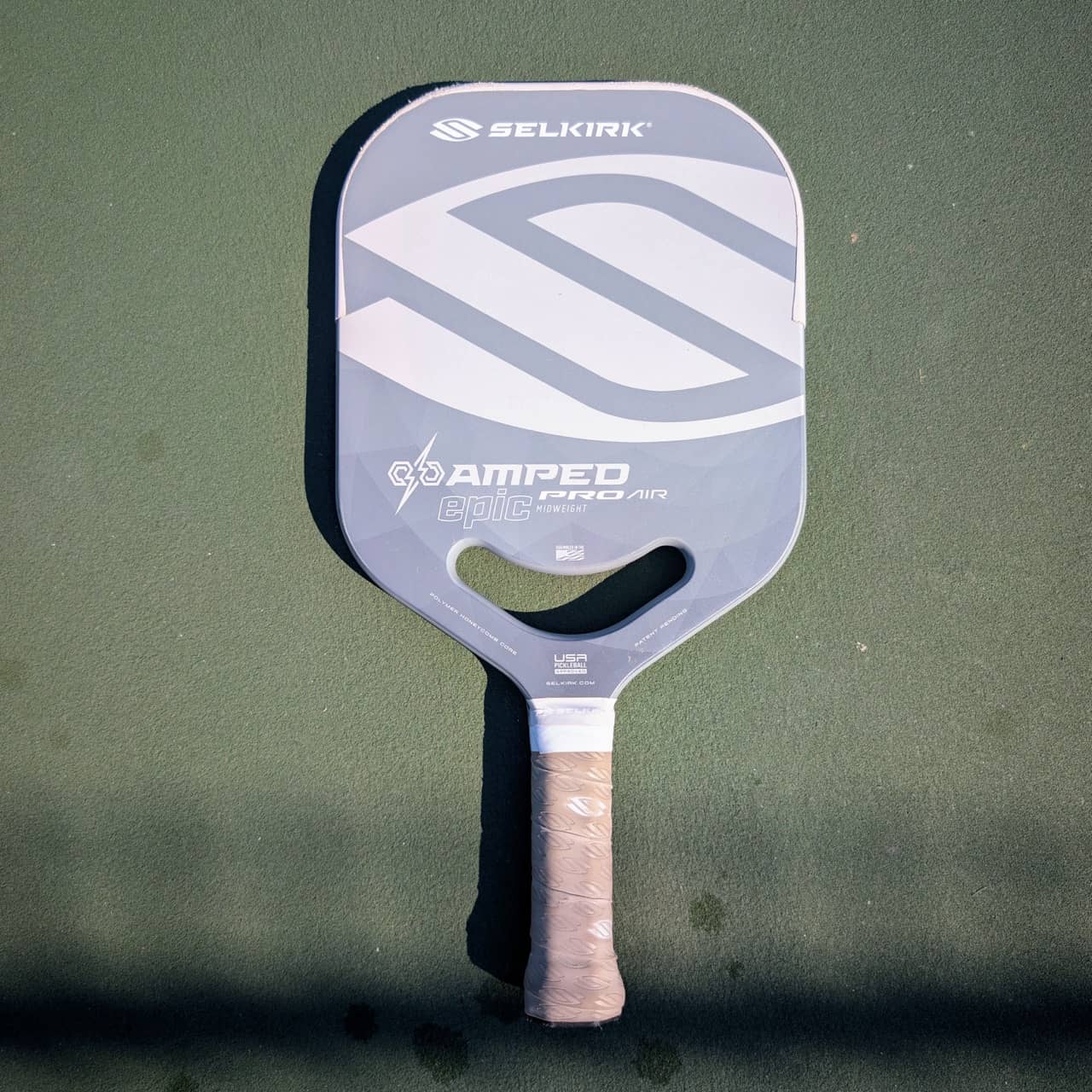 Selkirk Amped Pro Air Epic pickleball paddle with aero handle, gray and white, on a pickleball court