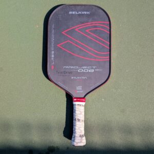 Selkirk LABS Project 008 pickleball paddle, PureForm, Invikta face, red and black, on a pickleball court