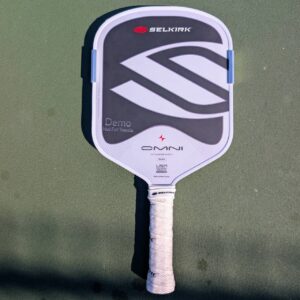 Selkirk Omni pickleball paddle, widebody shape, white and gray, on a pickleball court