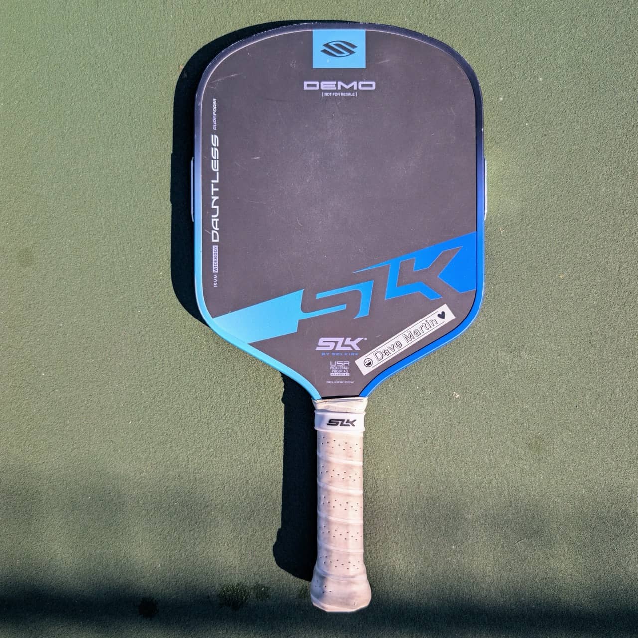 Selkirk SLK Dauntless PureForm pickleball paddle, widebody shape, blue, on a pickleball court