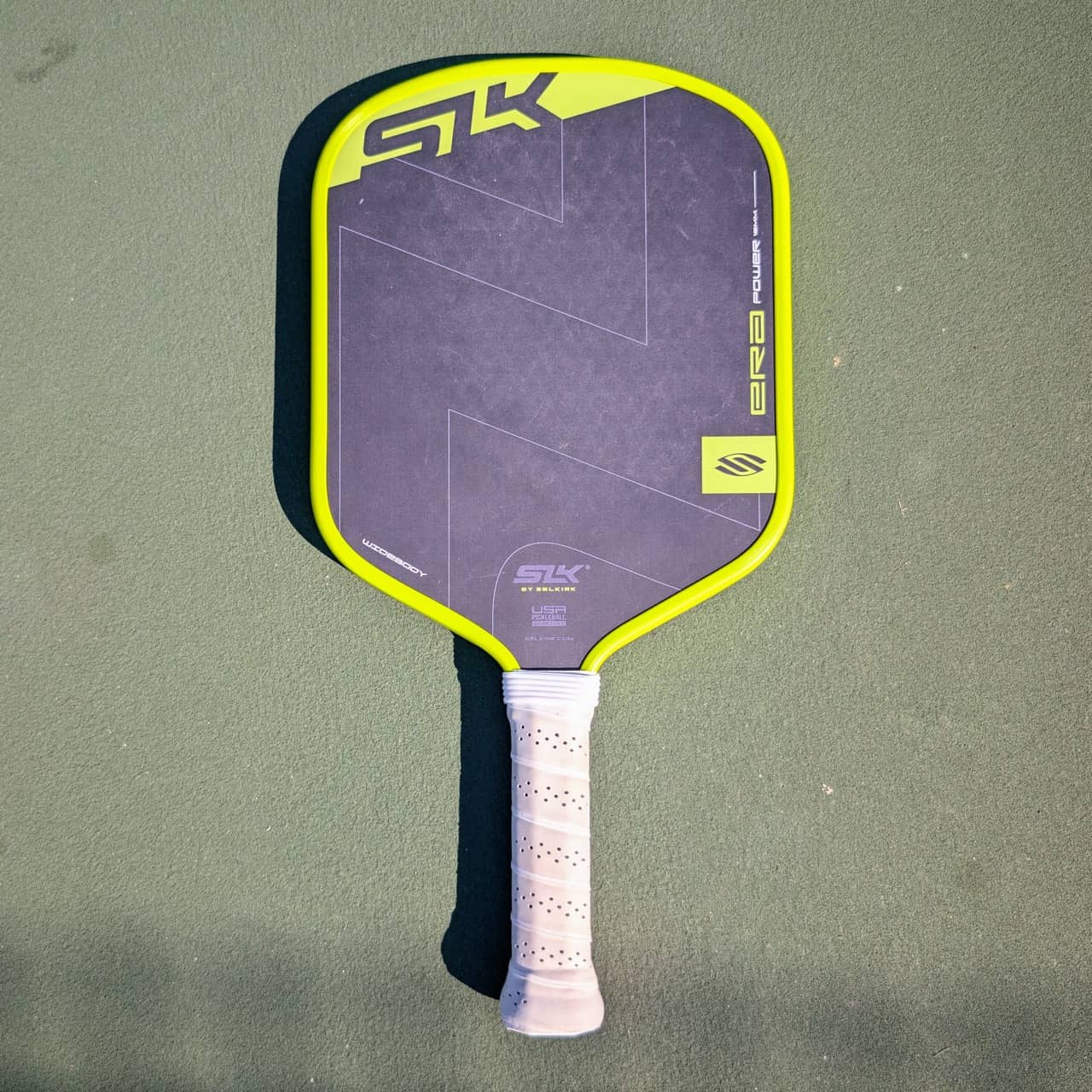 Selkirk SLK Era Power pickleball paddle, widebody shape, yellow and black, on a pickleball court
