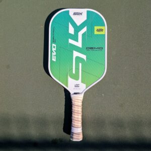 Selkirk SLK Evo Control XL pickleball paddle, green and teal, on a pickleball court
