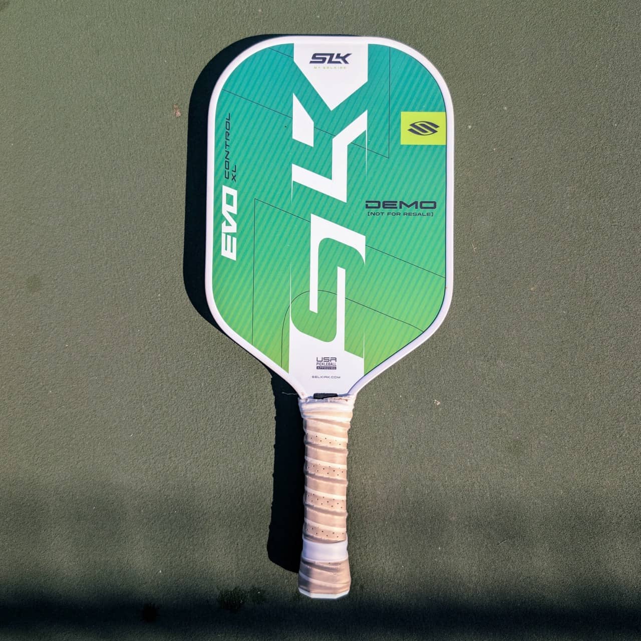 Selkirk SLK Evo Control XL pickleball paddle, green and teal, on a pickleball court