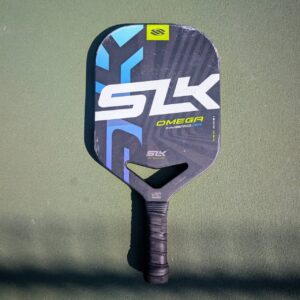 Selkirk SLK Omega Hybrid Air pickleball paddle with aero handle, blue and black, on a pickleball court