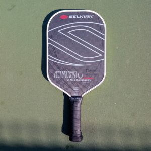 Selkirk Vanguard Pro Invikta pickleball paddle, black and gray, midweight, on a pickleball court