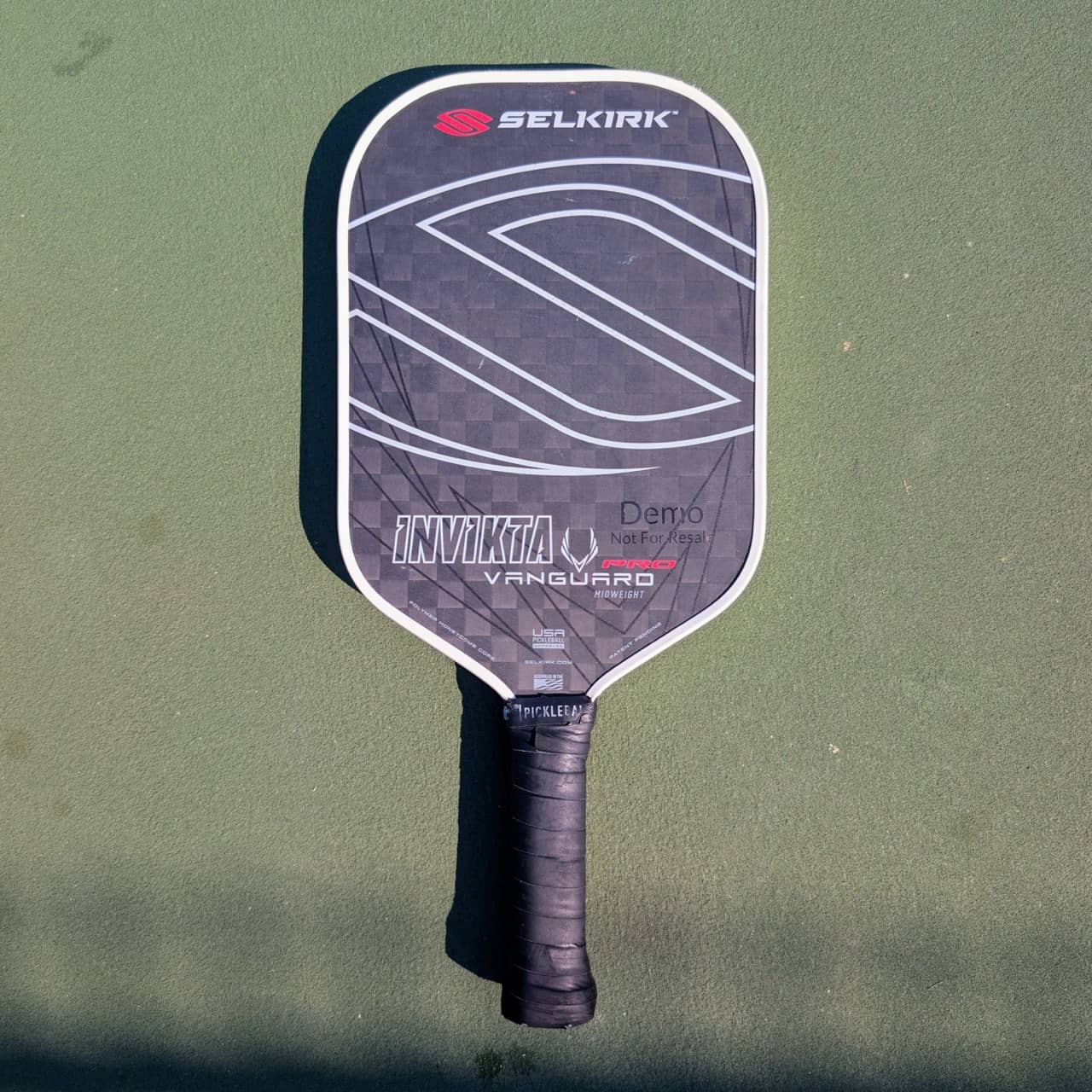 Selkirk Vanguard Pro Invikta pickleball paddle, black and gray, midweight, on a pickleball court